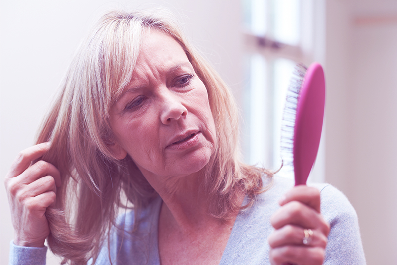 Woman noticing unusual loss of hair in hair brush