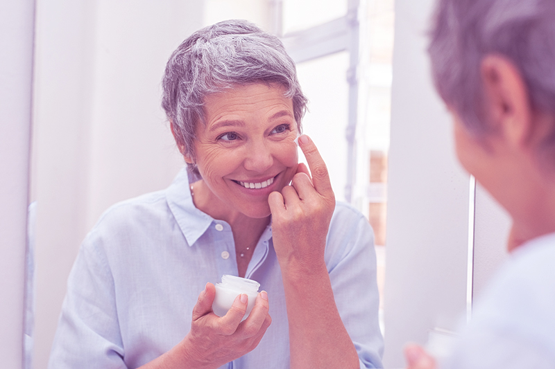 woman over 50 in menopause applying skin cream