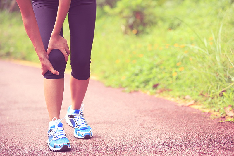 a female running holding her knee with joint pain