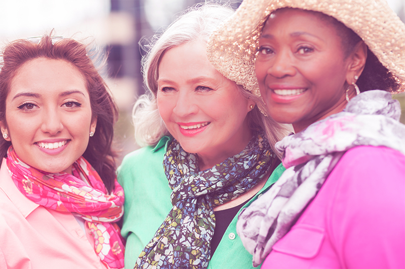 three smiling women in scarves