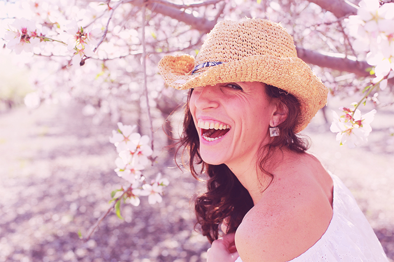 woman over 50 in a straw hat outside with cherry blossoms