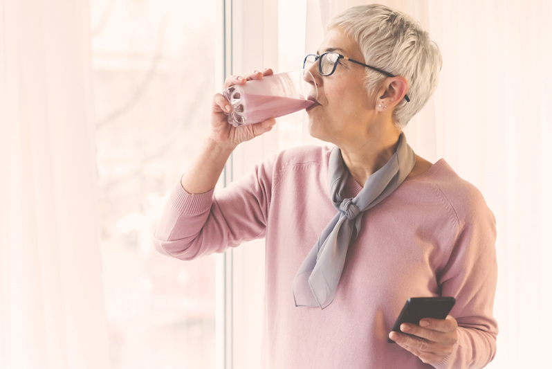 gray haired woman drinking a protein smoothie