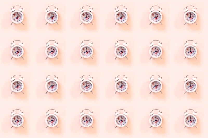 clocks on a pink background representing intermittent fasting