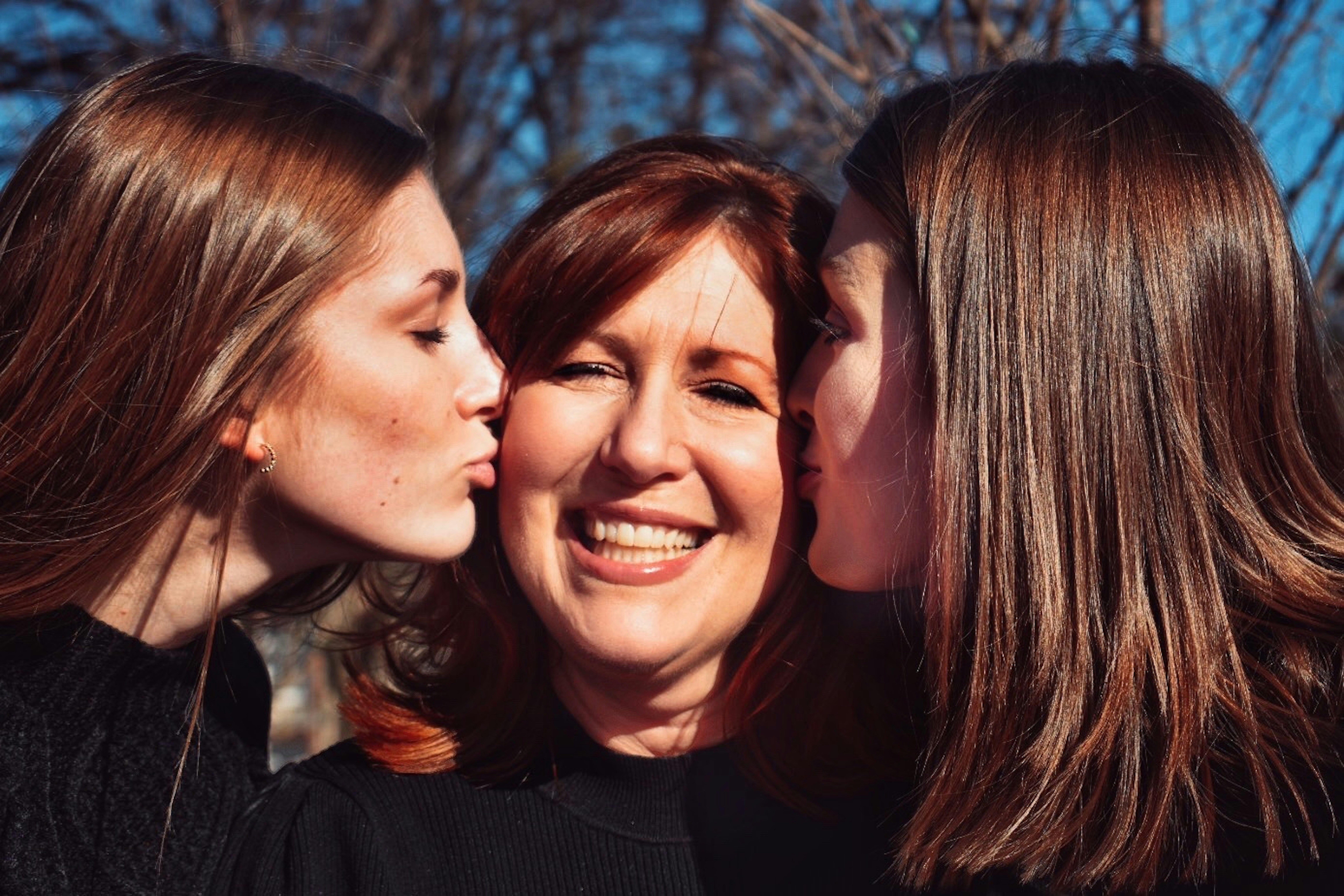 2 daughters kissing mom