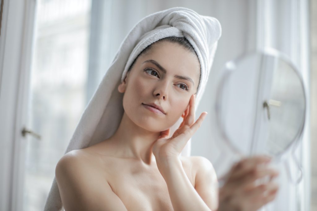 Woman looking in the mirror using hyaluronic acid