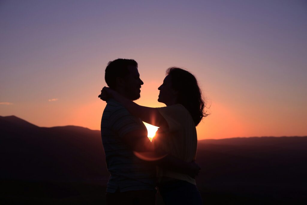woman and man holding each other at sunset