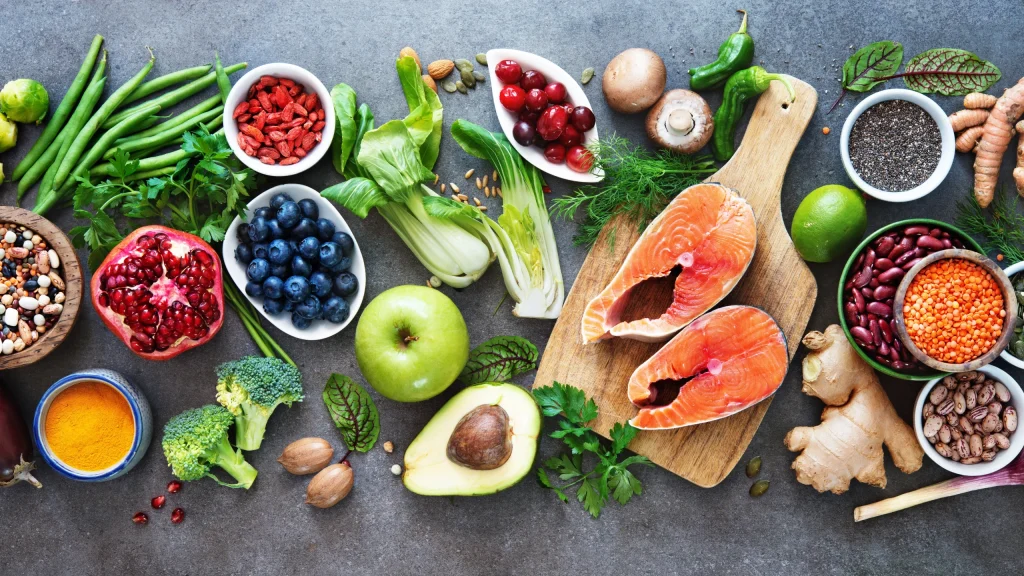 A table filled with fresh food including berries, apples, avocado, vegetables, and fish