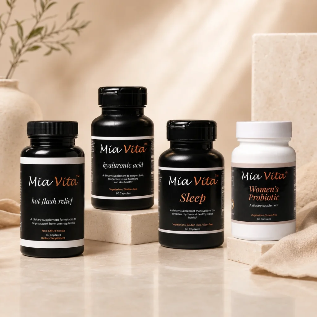 Four Mia Vita supplements—Hot Flash Relief, Hyaluronic Acid, Sleep, and Women’s Probiotic—arranged on neutral stone risers in a warm, elegant wellness setting.