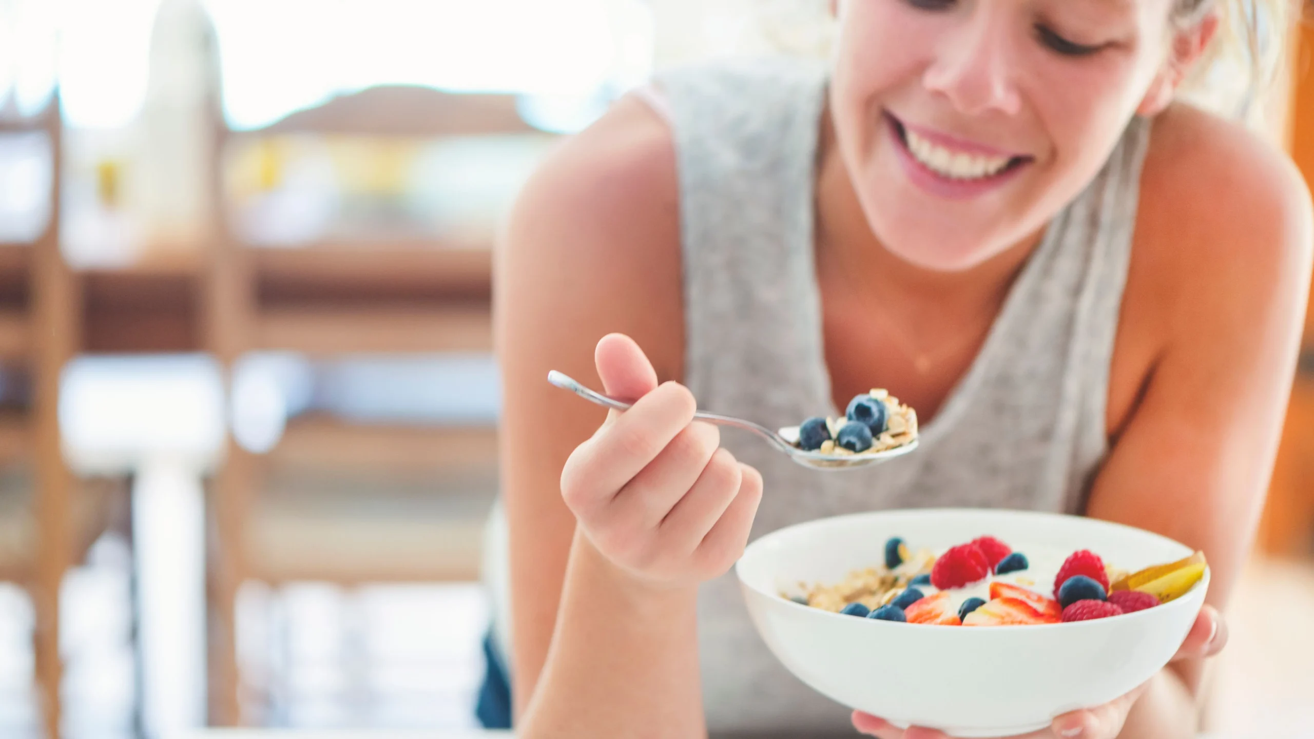 Blood Sugar and Anxiety Woman eating a breakfast bowl with berries, oats, and fruit.